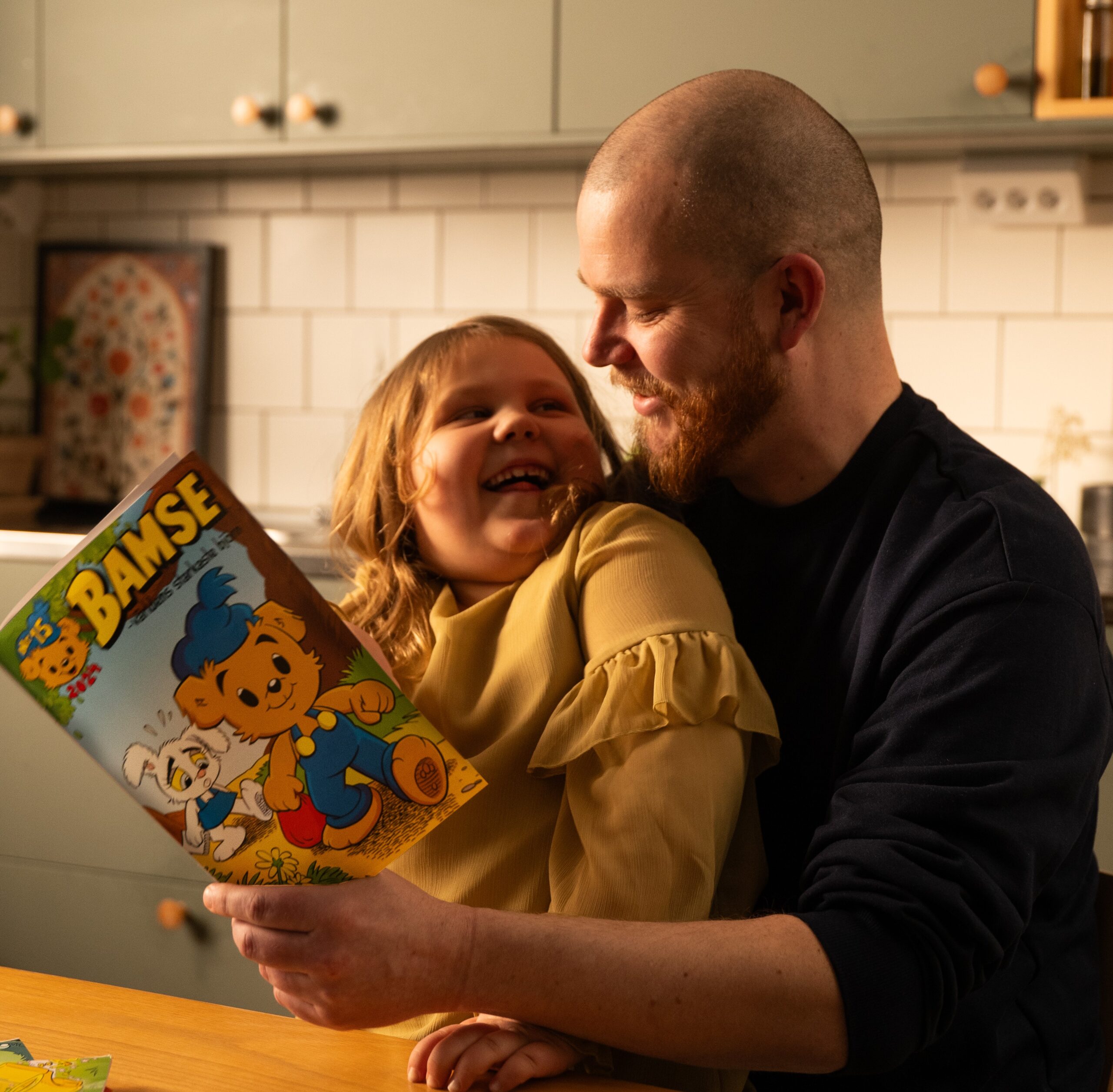 Pappa och dotter läser Bamsetidning.